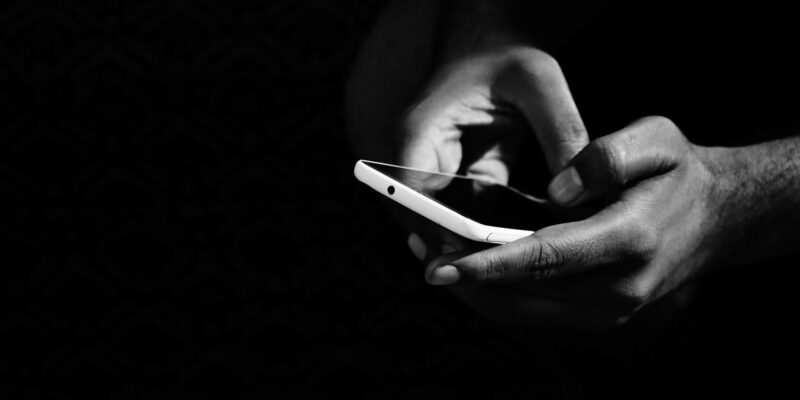 grey scale photo of person holding smartphone