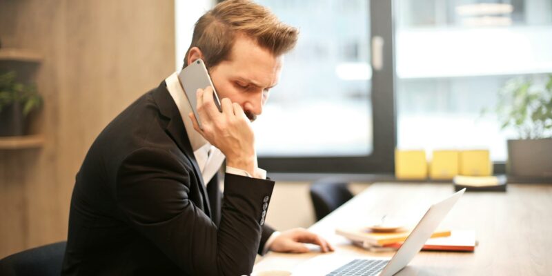 man having a phone call in front of a laptop